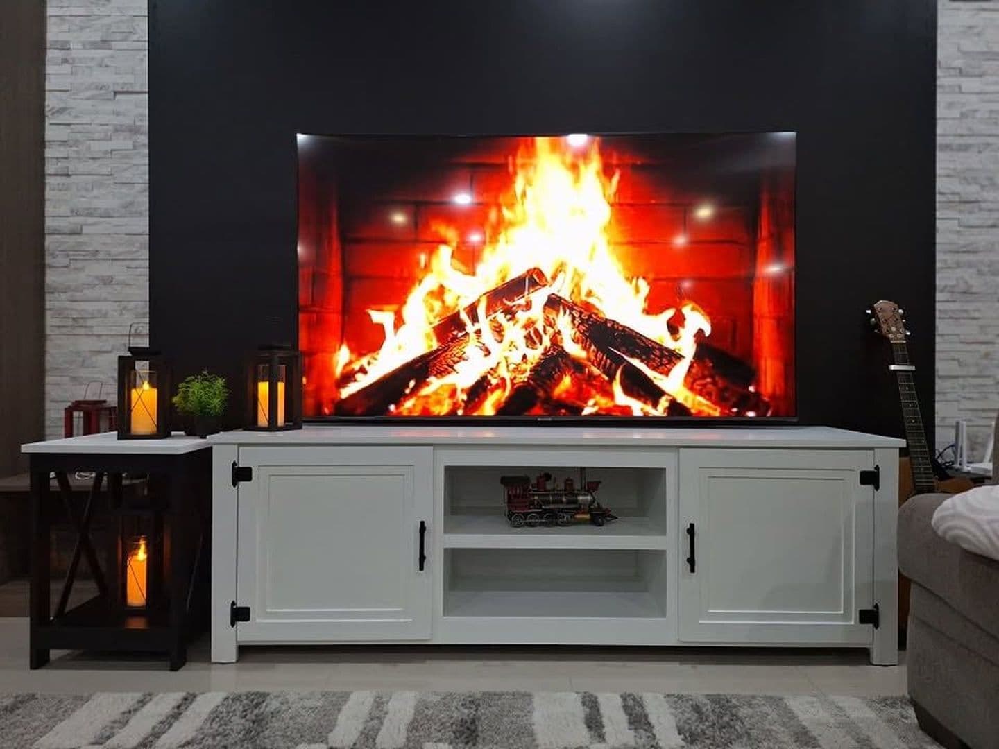White farmhouse TV console with black strap hinges, a matching side table and candle lanterns