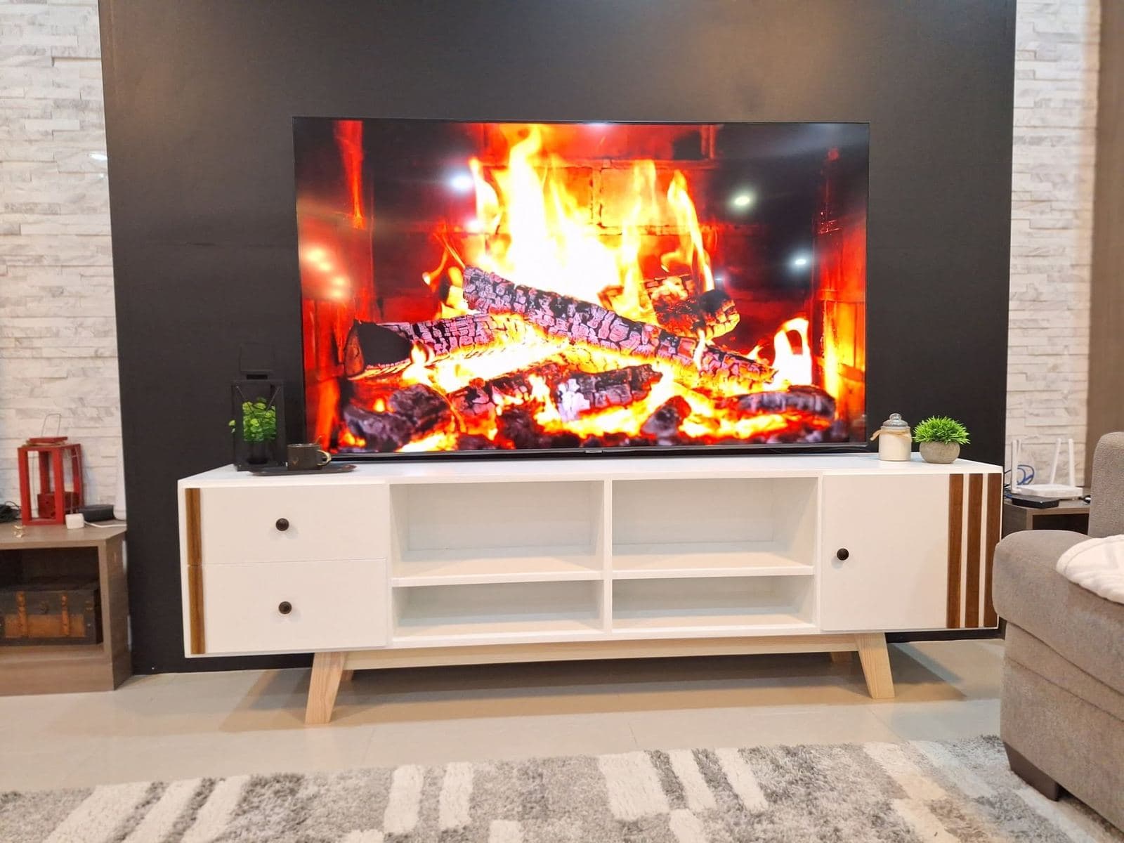 White mid-century TV console on splayed wooden legs with walnut-slat end panels