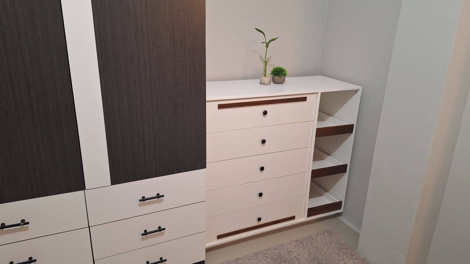 White six-drawer dresser with inset walnut pulls beside open cubby shelving